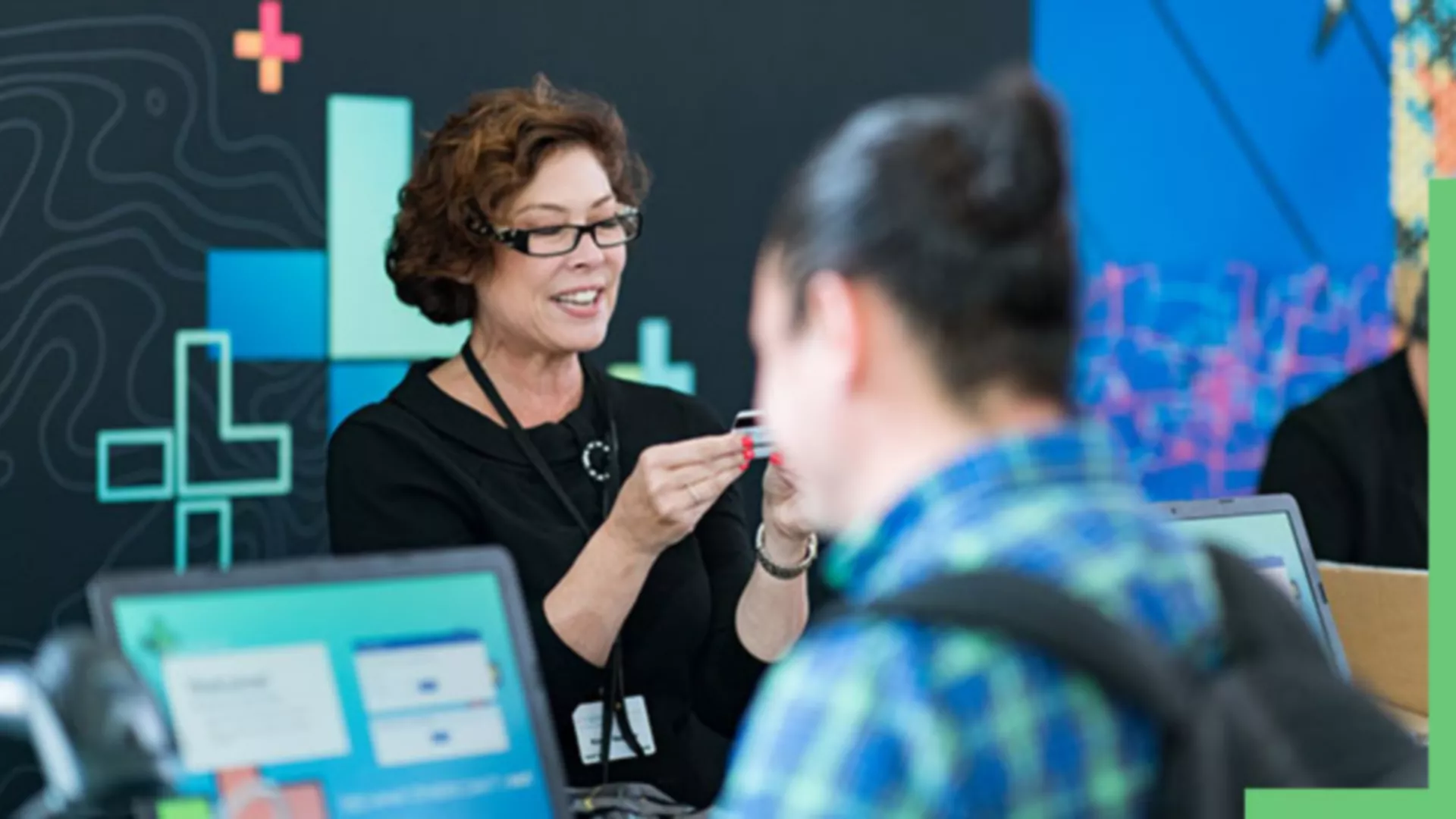 An employee looking at an identification card with a person using a computer in front of them