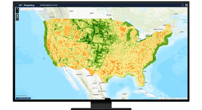 A green and yellow map of the United States, a person in business attire working on a tablet