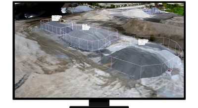 A desktop computer screen showing three stockpiles of gravel surrounded by pink 3D lines showing width and height and calculations hovering of the piles showing the resource volumes 