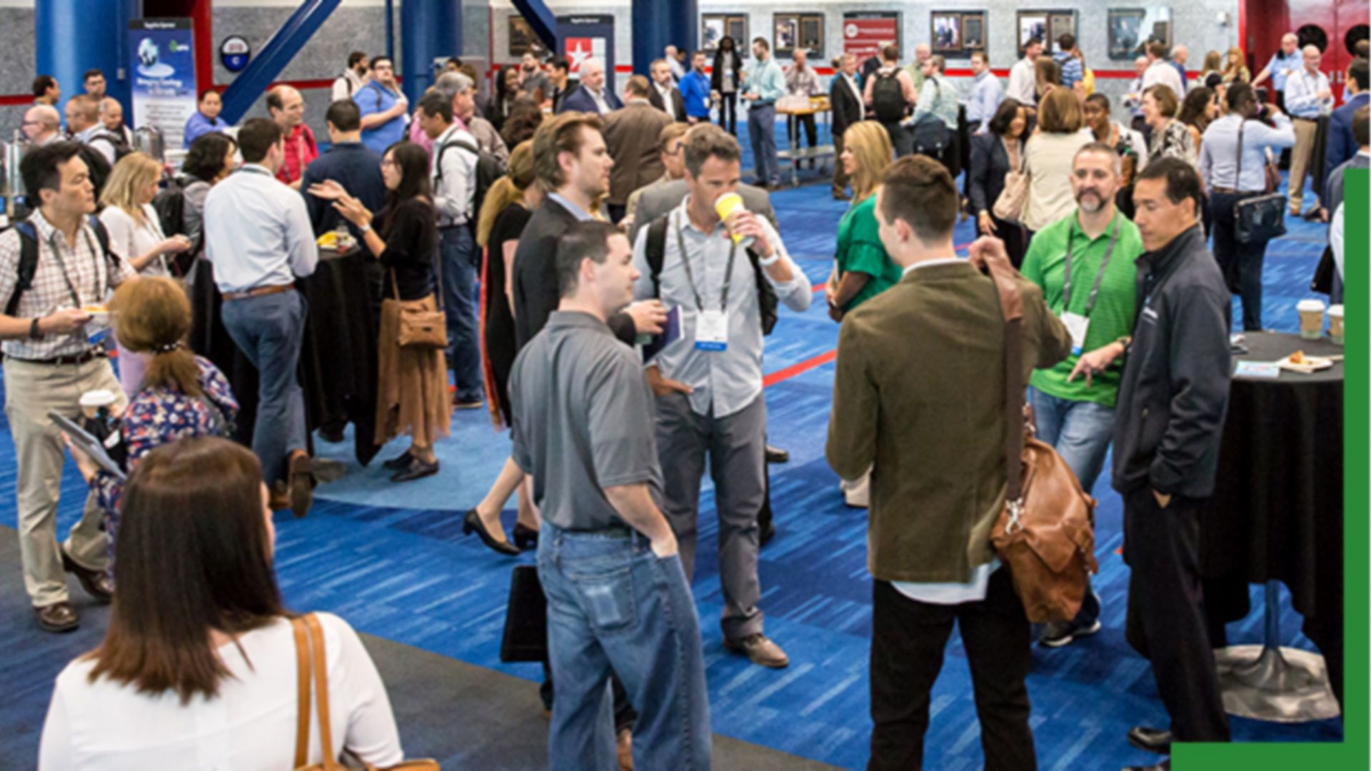 A photo of a crowded exhibit hall full of casually dressed attendees laughing and talking