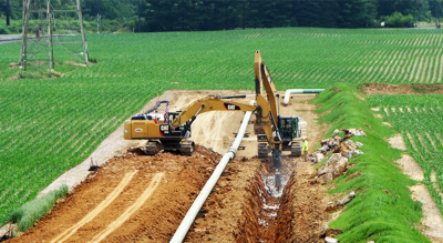 A green sign that reads “Wetland Boundary” in front of a pipeline