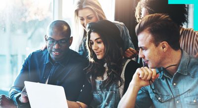 A group of people gathered around a laptop in a modern office setting