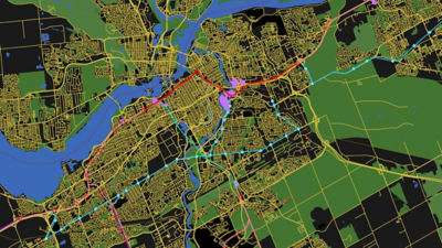 A dark-themed map showing dense city street networks, a river, and highlighted routes in red, pink, and blue across the urban area
