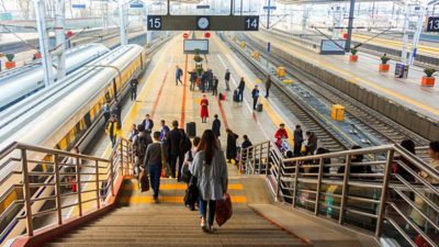 A crowded stairway leading to a train platform in a large station