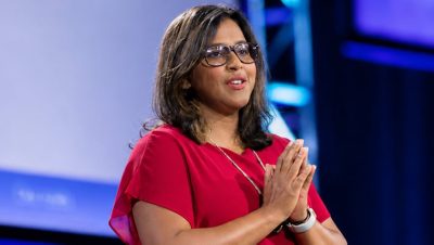 Presenter looks out from the stage with clasped hands