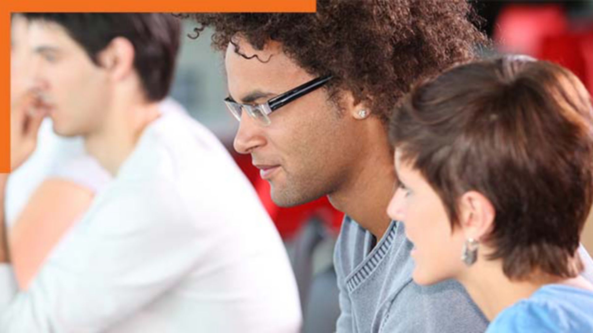 Zdjęcie trzech swobodnie ubranych uczestników seminarium w grupie, patrzących w lewo na niewidocznego mówcę lub ekran