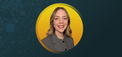 Portrait of Laine Alby smiling in a gray suit