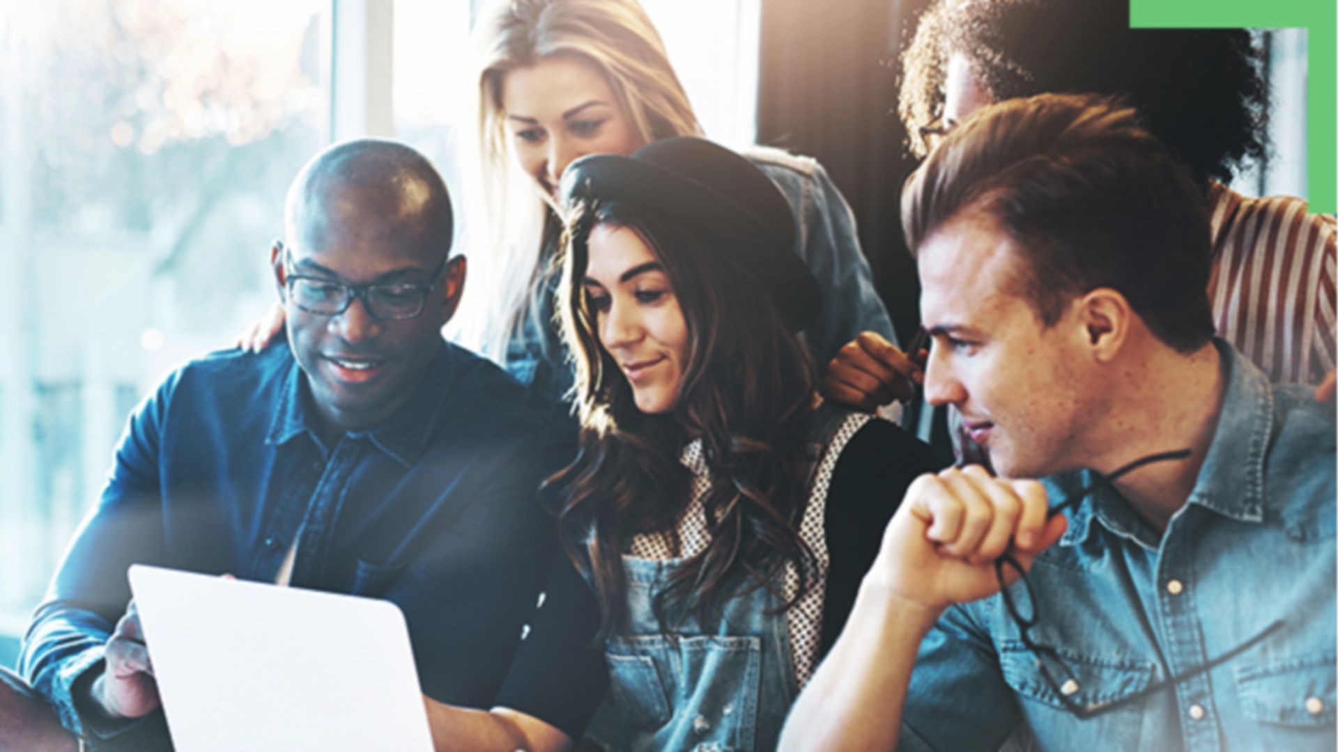 A group of five people looking at a laptop together