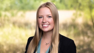 Retrato de Riley Winkler sorrindo em uma blusa azul e blazer preto