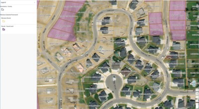 An aerial map of a residential area with developed properties in orange and vacant lots in purple