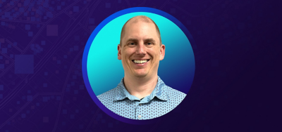 Portrait of Patrick Gross smiling in a patterned blue collared shirt