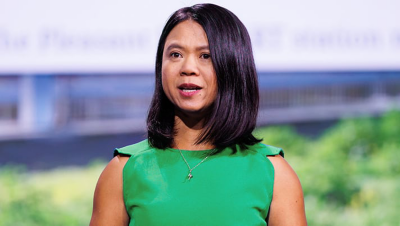 Presenter with shoulder-length dark hair wearing a green blouse