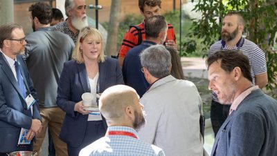 Attendees in business attire gathered in an atrium engaged in various conversations