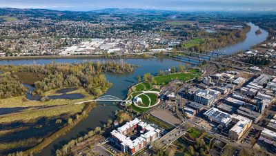 Aerial image of a tree-filled city spanning both sides of a wide river and several bridges