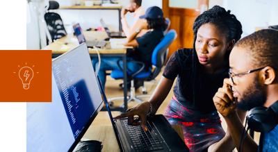 A man and woman in front a of a desktop computer looking at the screen