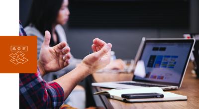 Man sitting at a table in front of a laptop with an open notebook and cellphone