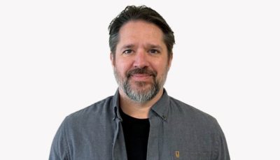 Matt Harman smiling in a black shirt in front of a white background