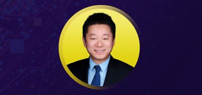 Yu Sun smiling in business attire on a yellow and purple background
