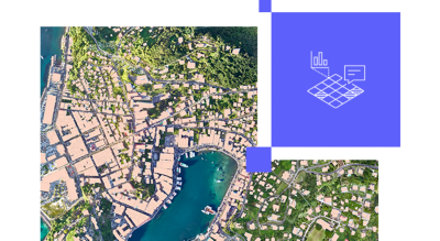 An aerial photograph showcases a coastal town with a harbor surrounded by lush greenery and residential areas.