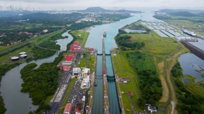 Panorámica del Canal de Panamá con un buque en tránsito y la ciudad al fondo.