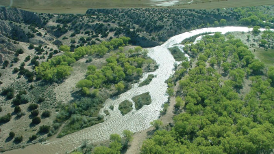 An aerial photograph of wooded hillsides intersected by a winding river with islands in the middle.