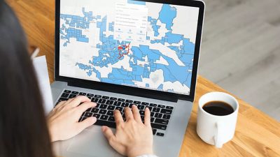 Eine Frau arbeitet am Laptop mit dem ArcGIS Business Analyst.