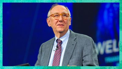 Jack Dangermond wearing a grey suit presenting on stage