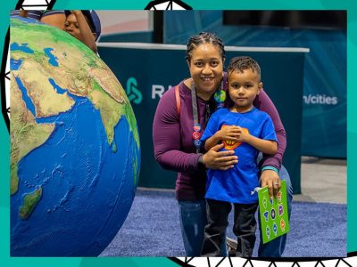 Adult and child standing next to a large globe display at Esri UC