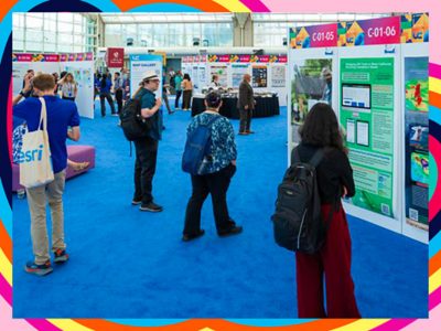 Attendees walk amongst colorful display booths showcasing diverse maps, photos, and information