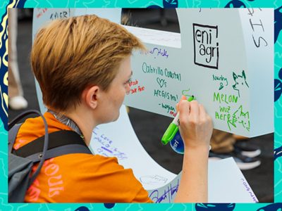 Event attendee signing a large white letter E with a green marker
