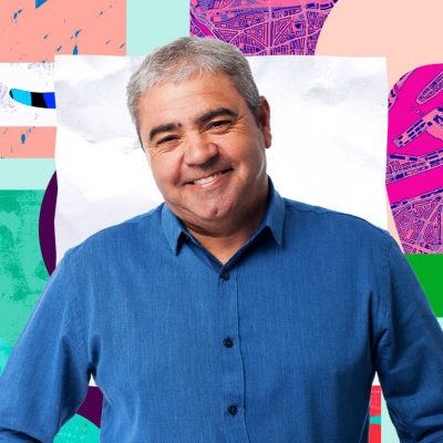 Smiling person with grey hair wearing a blue button up shirt