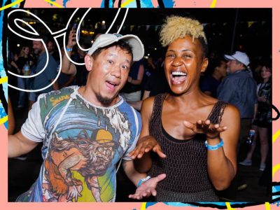 Two people enjoying a lively outdoor event at night standing close together with festive lights and crowd in the background