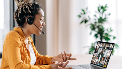 A businessperson with a headset and a laptop talking to her team on virtual meeting