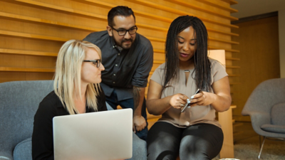 Three people in a seating area looking at one person’s phone
