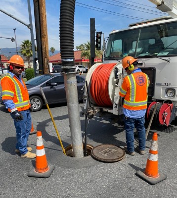 Workers in orange vests working on a manhole in the road