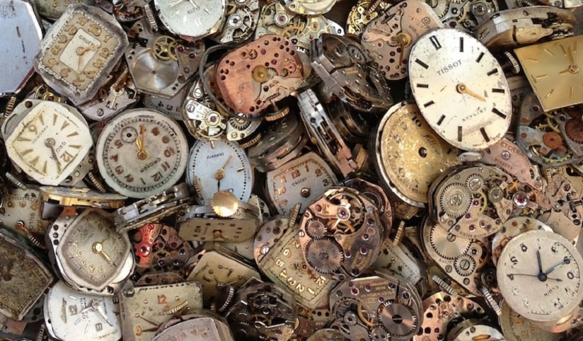 A close-up of watch faces and parts in a pile